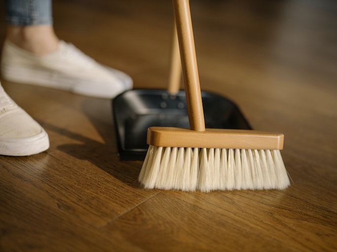 A broom and dust pan on a wooden floor